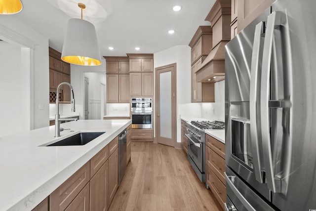 kitchen with pendant lighting, sink, light hardwood / wood-style flooring, light stone countertops, and appliances with stainless steel finishes