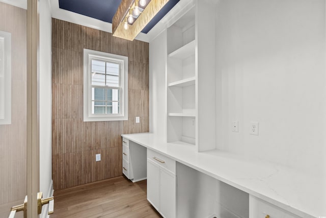 interior space featuring built in desk, light hardwood / wood-style floors, built in features, and wood walls