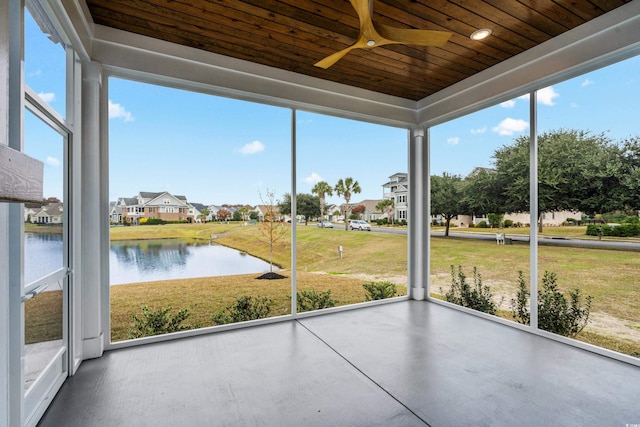 unfurnished sunroom featuring ceiling fan, a water view, and wood ceiling