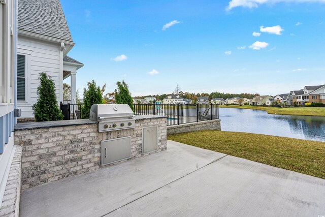 view of patio with an outdoor kitchen, a water view, and grilling area