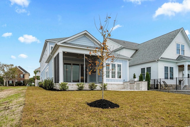 rear view of property featuring a sunroom and a lawn