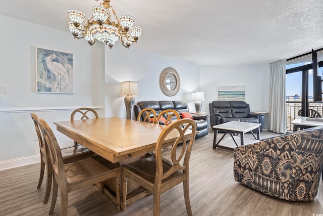 dining area with expansive windows, wood finished floors, a textured ceiling, an inviting chandelier, and baseboards