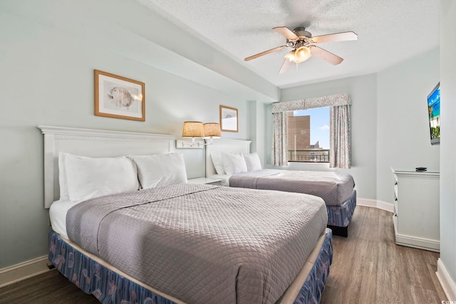 bedroom with ceiling fan, a textured ceiling, and dark hardwood / wood-style flooring