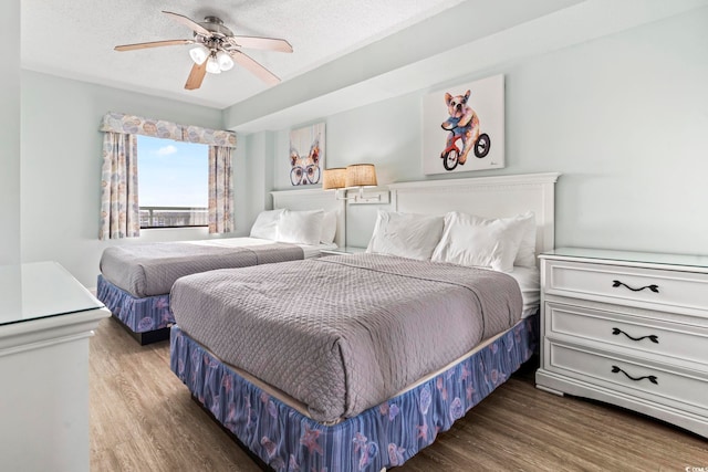 bedroom with hardwood / wood-style flooring, ceiling fan, and a textured ceiling