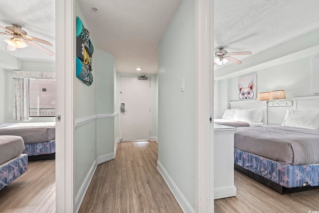 corridor featuring a textured ceiling, baseboards, and wood finished floors