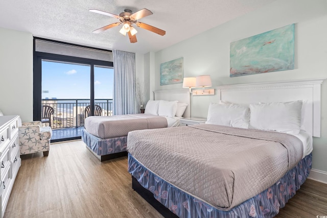 bedroom with a ceiling fan, access to outside, a textured ceiling, and wood finished floors