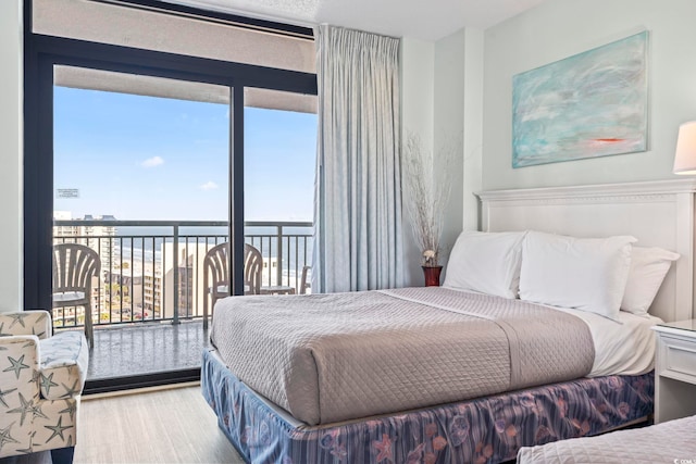 bedroom with a water view, wood finished floors, and access to exterior