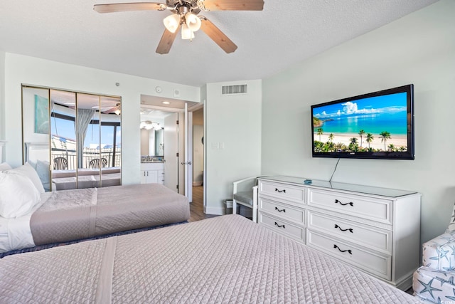 bedroom with ceiling fan, a textured ceiling, and connected bathroom