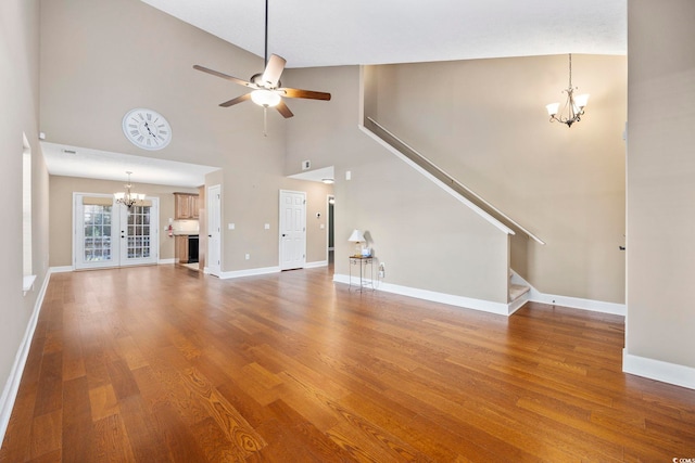 unfurnished living room featuring high vaulted ceiling, wood-type flooring, french doors, and ceiling fan with notable chandelier