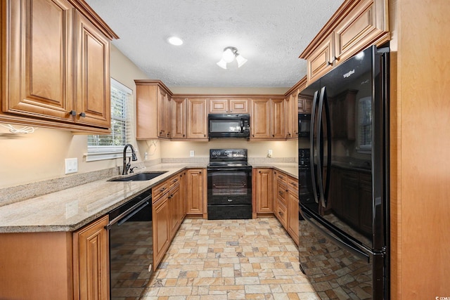 kitchen with a textured ceiling, black appliances, sink, and light stone counters