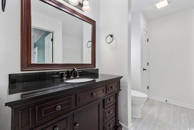 bathroom featuring toilet, vanity, and hardwood / wood-style flooring