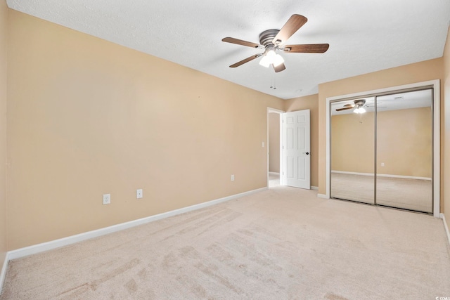 unfurnished bedroom with ceiling fan, a textured ceiling, a closet, and light colored carpet