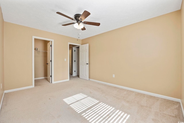 unfurnished bedroom with ceiling fan, light carpet, a closet, and a spacious closet