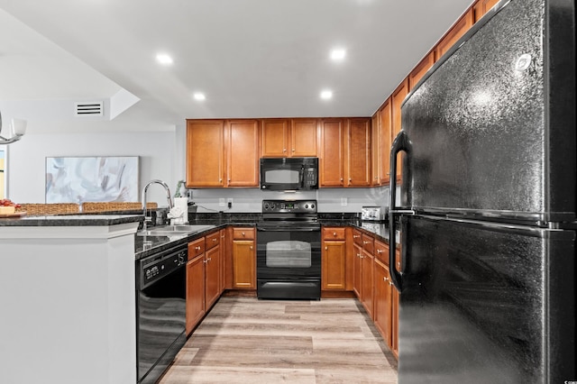 kitchen featuring black appliances, kitchen peninsula, sink, and light hardwood / wood-style flooring