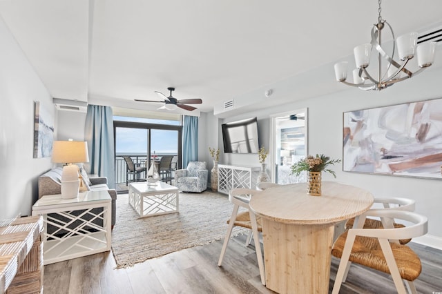 dining space with hardwood / wood-style flooring, ceiling fan with notable chandelier, and a wealth of natural light