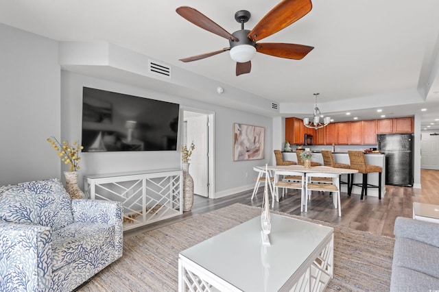 living room with light hardwood / wood-style floors and ceiling fan with notable chandelier