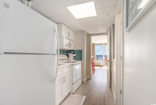 kitchen with backsplash, a drop ceiling, white appliances, light hardwood / wood-style flooring, and white cabinetry