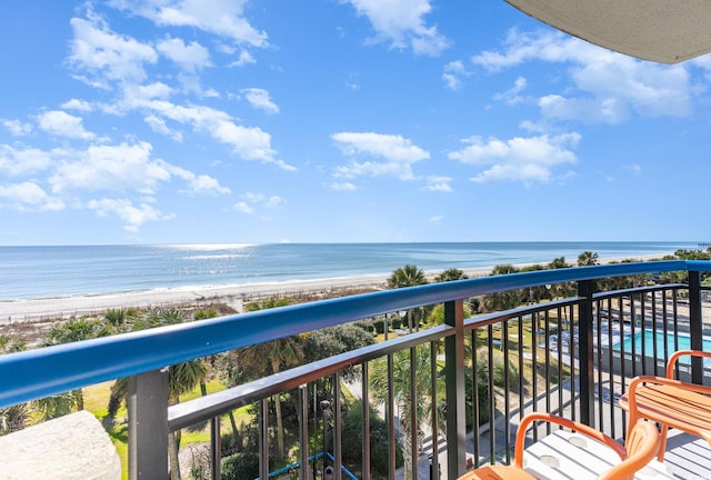 balcony with a water view and a view of the beach