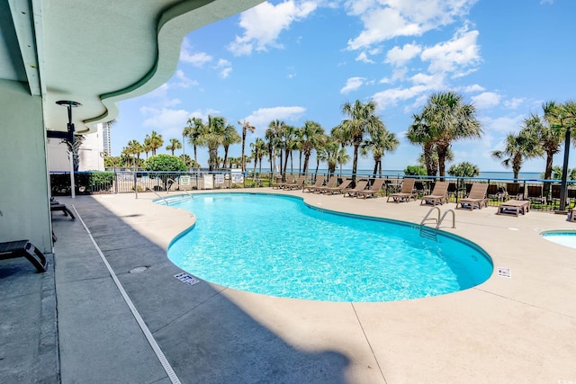 view of pool featuring a patio and a water view