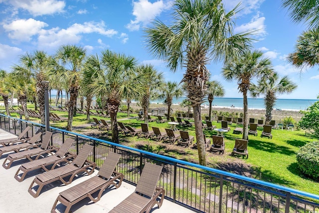 view of community featuring a lawn, a water view, and a view of the beach