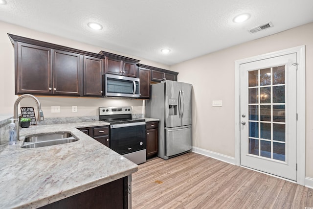 kitchen featuring sink, appliances with stainless steel finishes, a textured ceiling, dark brown cabinets, and light wood-type flooring