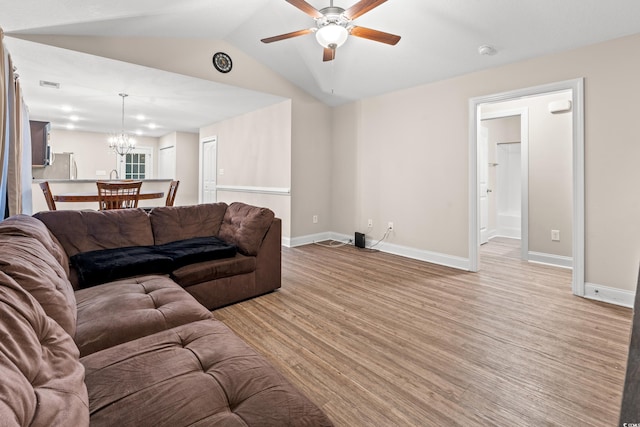 living room with light wood-type flooring, vaulted ceiling, and ceiling fan with notable chandelier