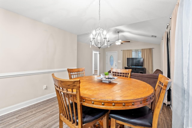 dining space with hardwood / wood-style flooring, ceiling fan with notable chandelier, and lofted ceiling