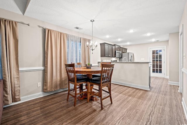 dining room featuring dark hardwood / wood-style flooring, a notable chandelier, and a textured ceiling