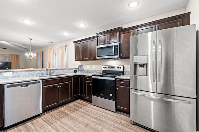 kitchen with pendant lighting, stainless steel appliances, a textured ceiling, and light hardwood / wood-style flooring