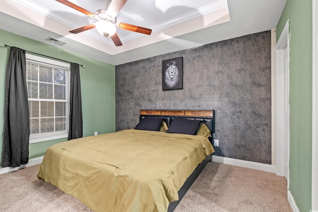 carpeted bedroom featuring a tray ceiling, ceiling fan, and crown molding