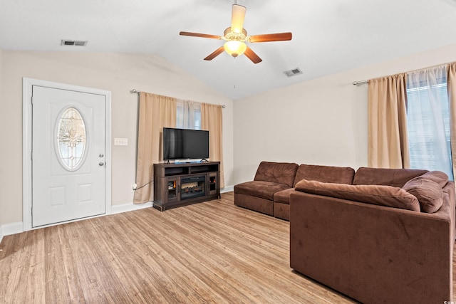 living room with light wood-type flooring, vaulted ceiling, ceiling fan, and plenty of natural light