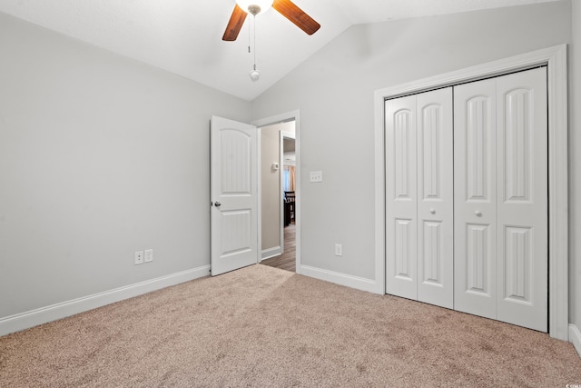 unfurnished bedroom featuring a closet, vaulted ceiling, light colored carpet, and ceiling fan