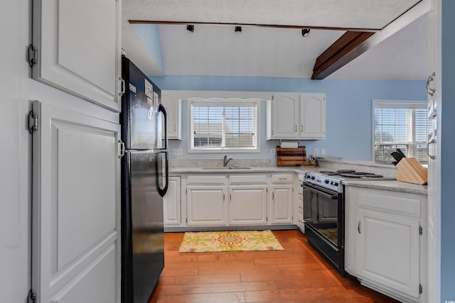 kitchen with black appliances, white cabinetry, a healthy amount of sunlight, and beam ceiling