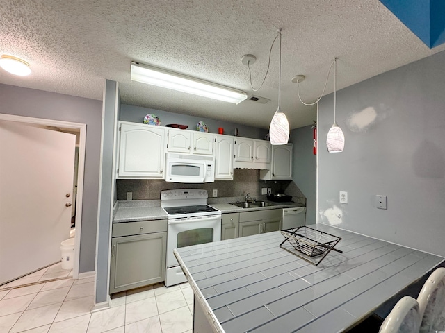 kitchen featuring white appliances, sink, decorative light fixtures, a textured ceiling, and tile counters