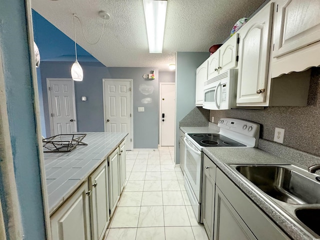 kitchen with white appliances, sink, hanging light fixtures, a textured ceiling, and tile counters