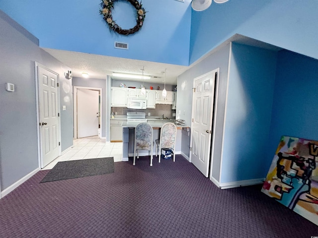 kitchen with white appliances, light colored carpet, sink, white cabinets, and a breakfast bar area