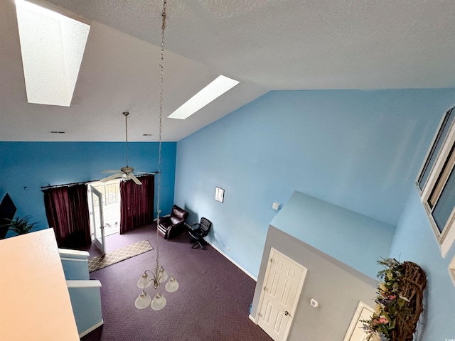 interior space featuring ceiling fan, carpet floors, high vaulted ceiling, and a skylight