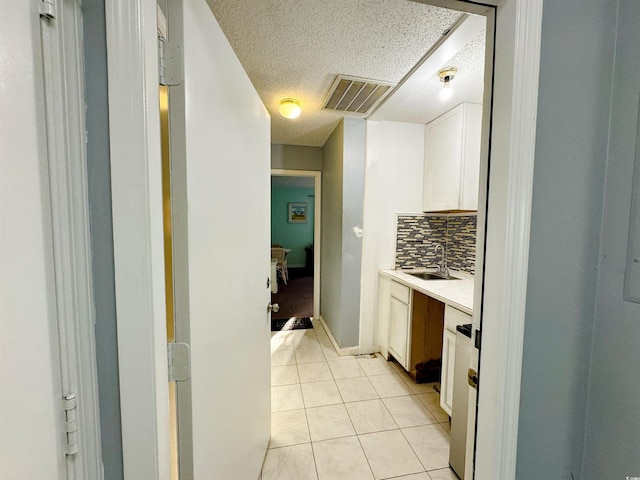 kitchen with decorative backsplash, white cabinetry, sink, and light tile patterned floors