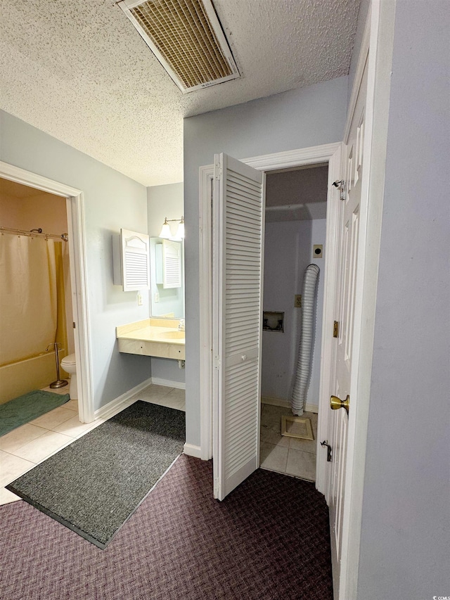 bathroom with tile patterned flooring, a textured ceiling, and toilet