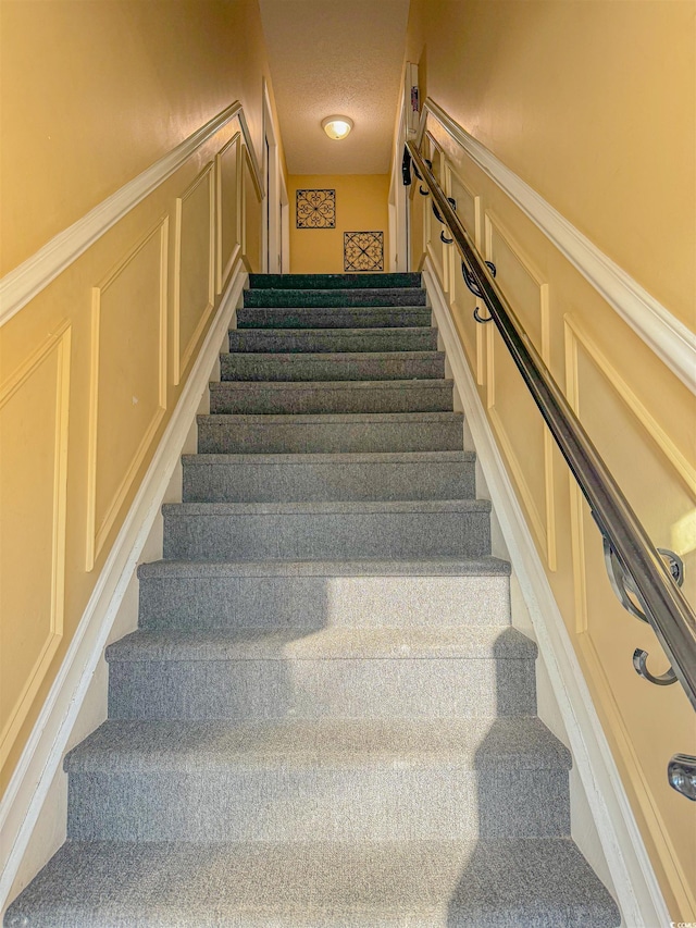 staircase featuring a textured ceiling