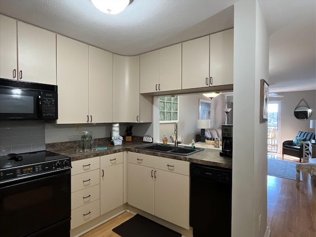 kitchen featuring white cabinets, light hardwood / wood-style floors, sink, and black appliances