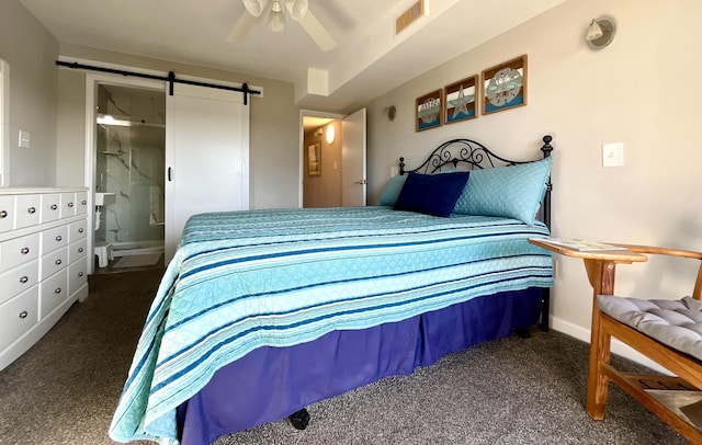 bedroom featuring ensuite bathroom, a barn door, ceiling fan, and dark colored carpet