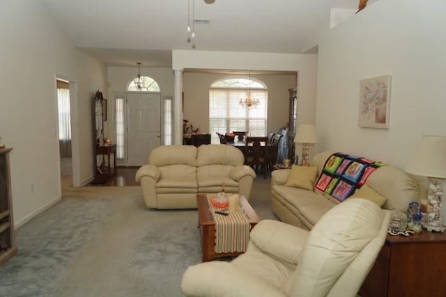 carpeted living room with a chandelier and decorative columns