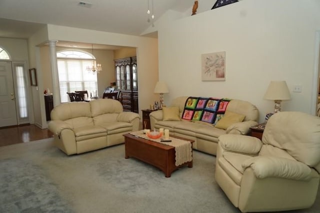 living room featuring light hardwood / wood-style floors, an inviting chandelier, lofted ceiling, and ornate columns