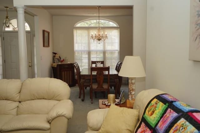 carpeted living room with a notable chandelier and ornate columns