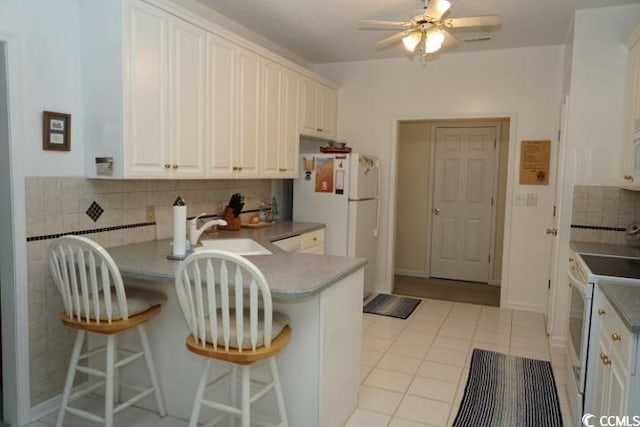 kitchen with white appliances, decorative backsplash, sink, and white cabinets