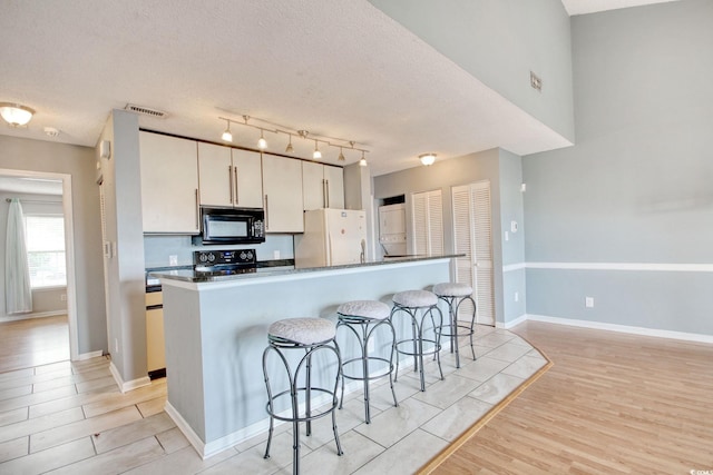 4337 Spa Dr Unit 1309, Little River, SC 29566 - kitchen with black microwave, freestanding refrigerator, range, a kitchen bar, and light wood-style floors