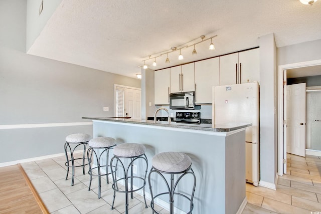 4337 Spa Dr Unit 1309, Little River, SC 29566 - kitchen featuring black microwave, freestanding refrigerator, a kitchen bar, range, and a textured ceiling