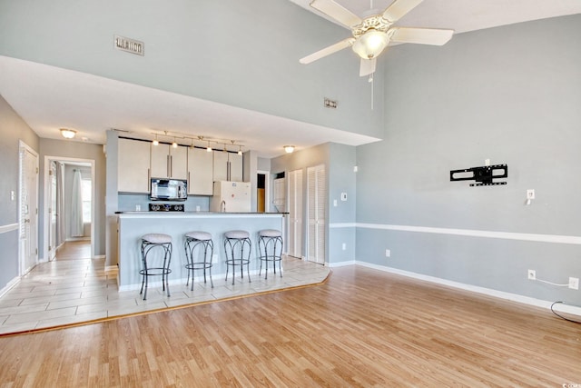 4337 Spa Dr Unit 1309, Little River, SC 29566 - kitchen with freestanding refrigerator, stainless steel microwave, light wood-style flooring, and a breakfast bar area