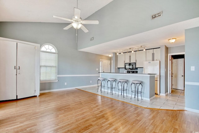 4337 Spa Dr Unit 1309, Little River, SC 29566 - kitchen featuring black microwave, a breakfast bar area, light wood-type flooring, freestanding refrigerator, and white cabinets